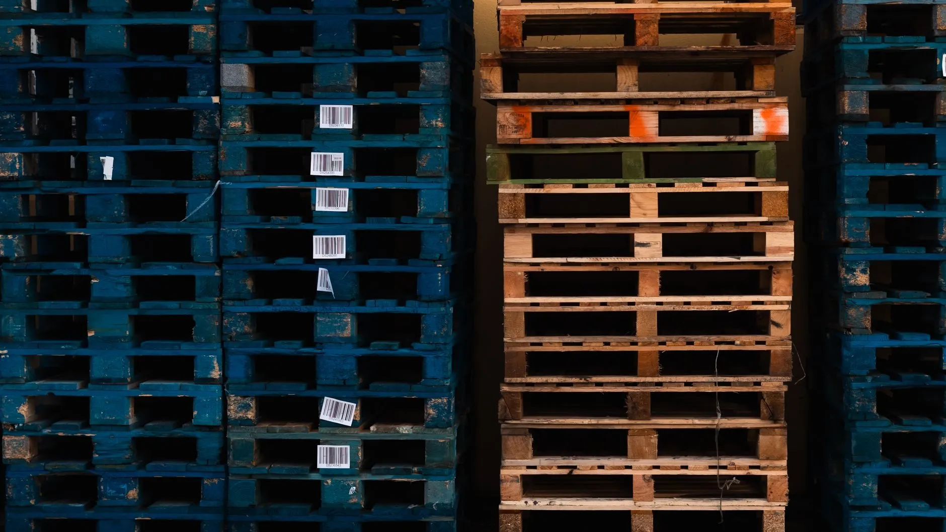 Stacks of blue and natural wooden pallets with barcode labels